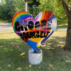 Heart-shaped sculpture with rainbow colors and text 
