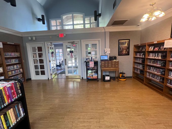 Library interior with bookshelves, doors to outside, and a small counter.
