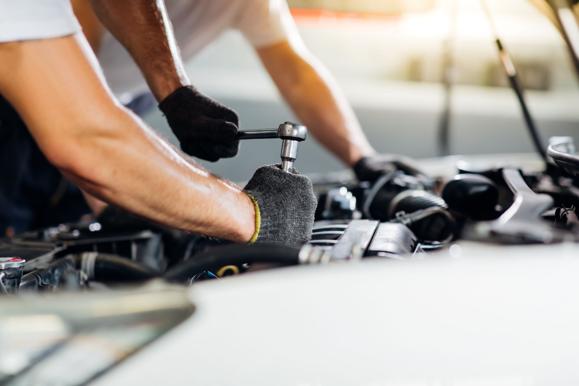 Two men are working on a car engine in a garage.