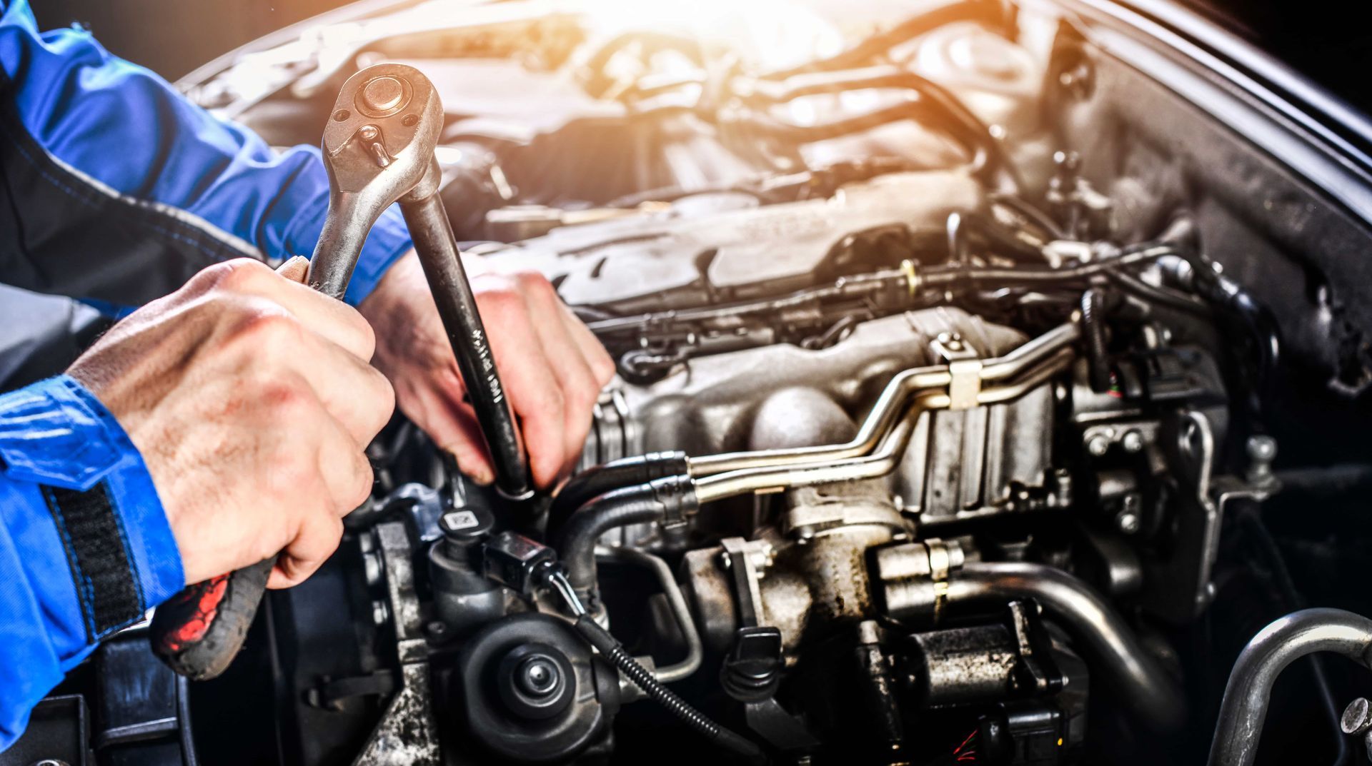 A mechanic is working on a car engine with a wrench.