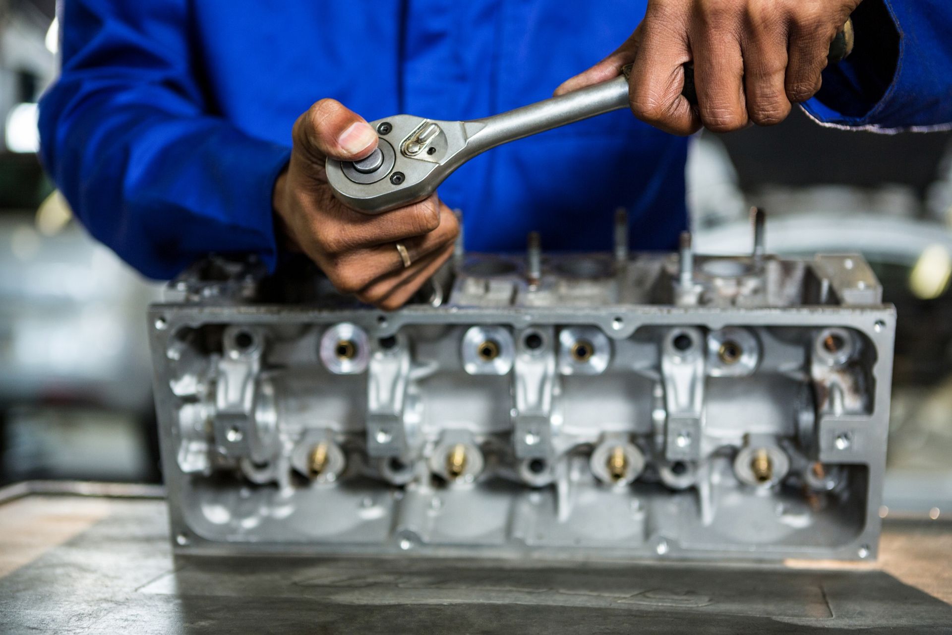 A man is working on a car engine with a wrench.