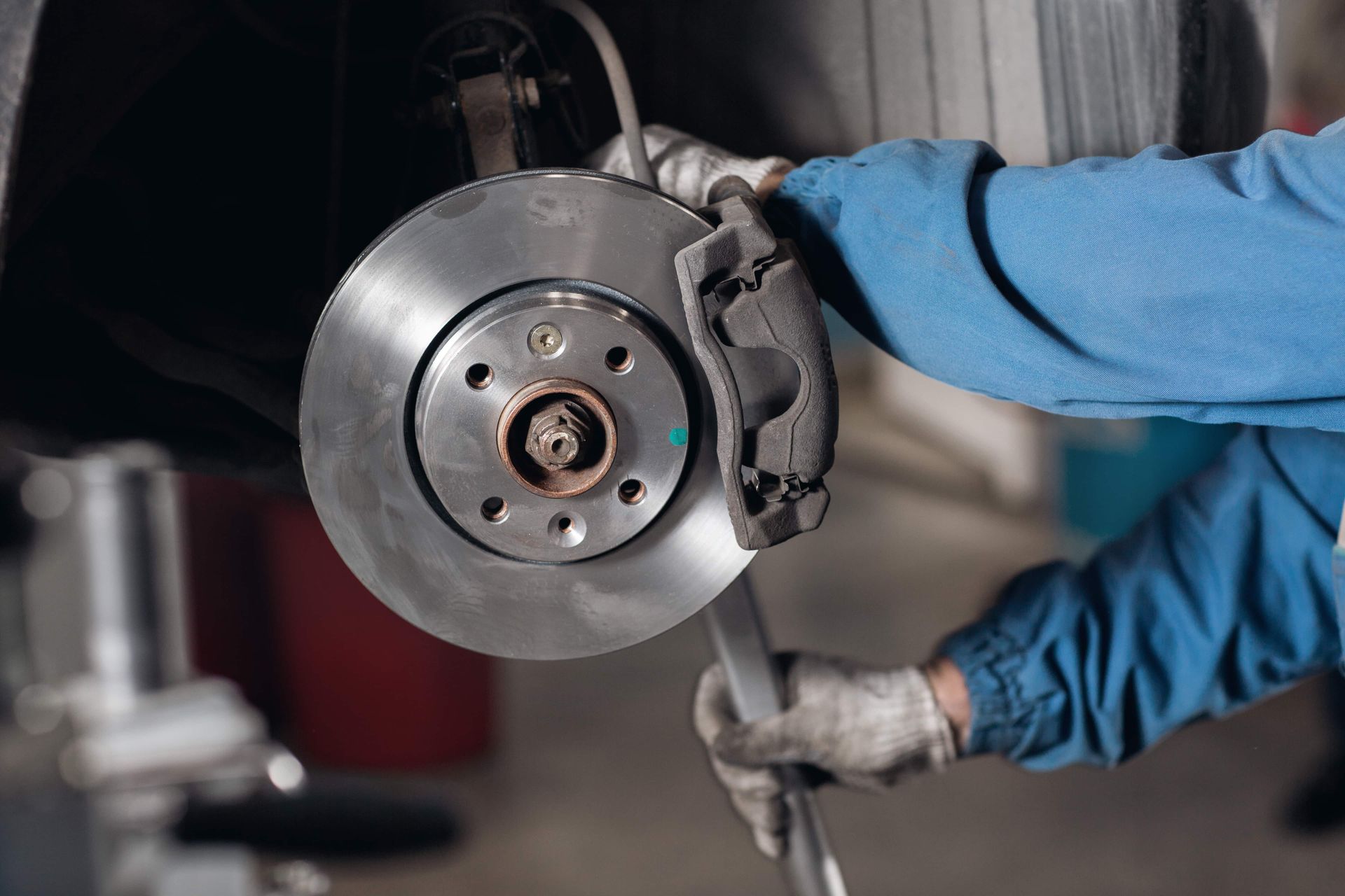 A mechanic is fixing a brake disc on a car with a wrench.
