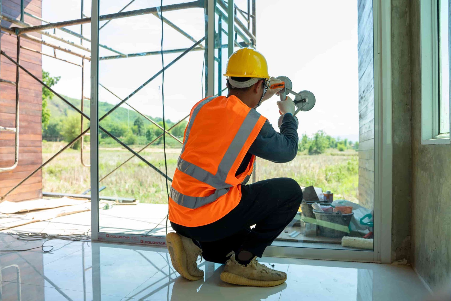 A Construction Worker is Installing a Window in a Building Under Construction — Twin Cities Glass In Albury, NSW