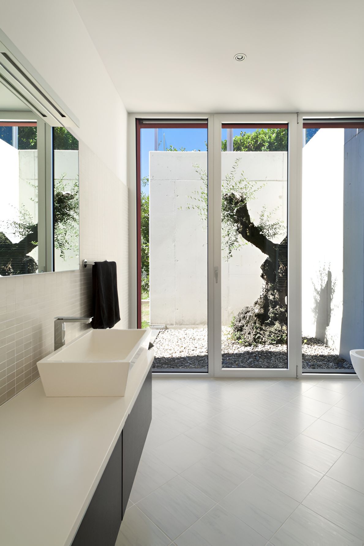 A Bathroom with white walls and a white sink and large glass window leading to outside — Twin Cities Glass In Albury, NSW