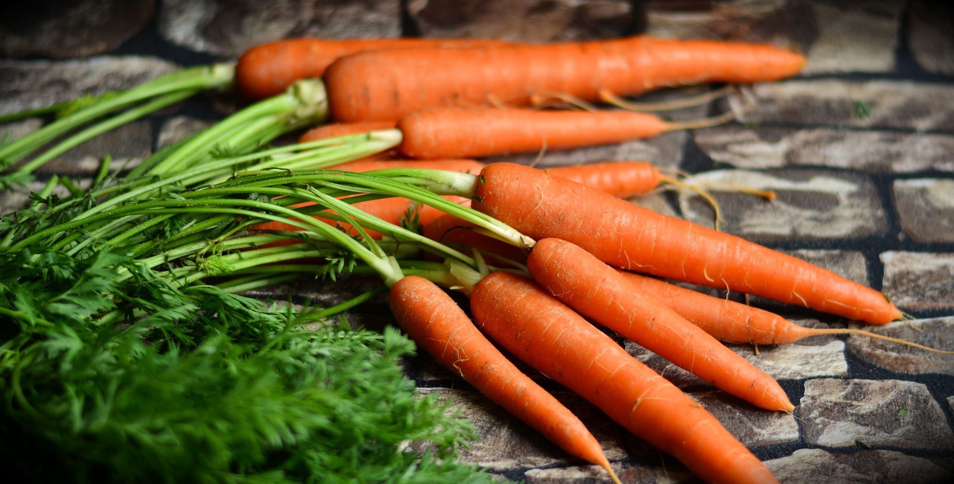 A bunch of carrots with green stems on a table.
