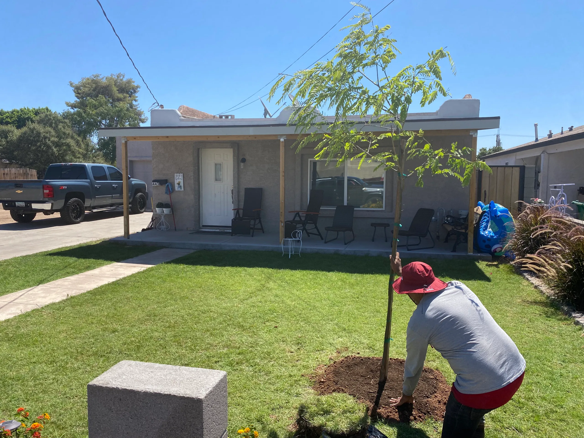 A man is planting a tree in front of a house.