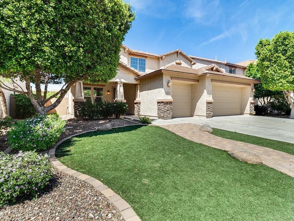 A large house with a lot of grass and trees in front of it.