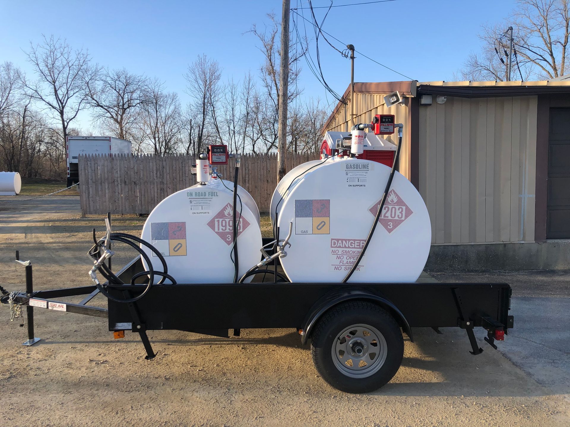 A trailer with two tanks on it is parked in front of a building.