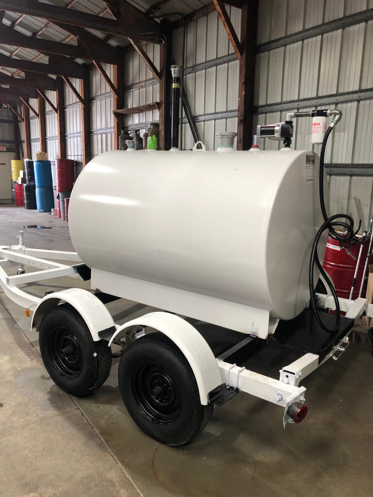 A large white tank is on a trailer in a warehouse.