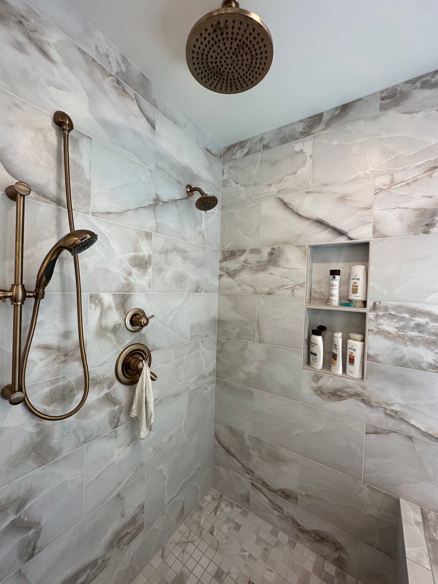 A bathroom with marble tiles and a shower head.