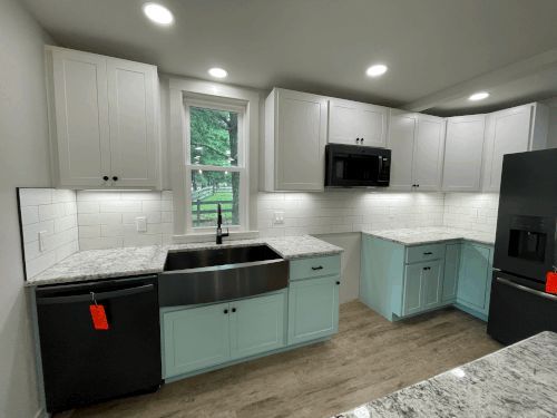 A kitchen with white cabinets , black appliances , a sink and a refrigerator.