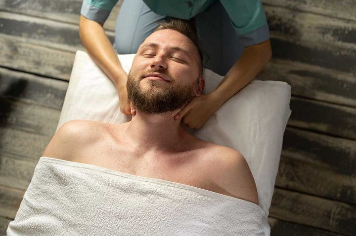 Massage therapist giving a back massage to a relaxed client on a treatment table