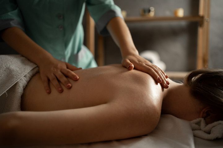 Massage therapist working on a client’s back in a spa setting