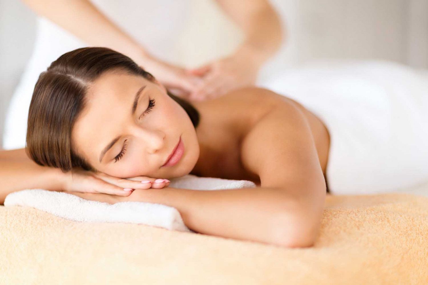 Woman receiving a massage, resting with eyes closed on a spa table