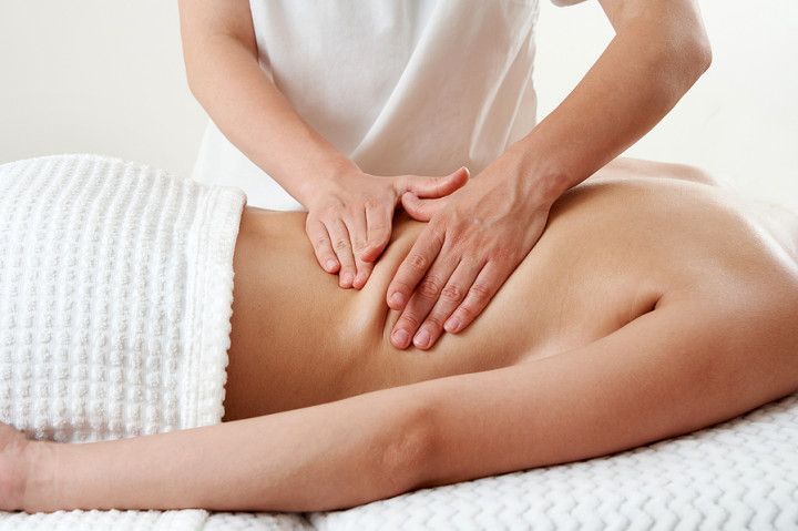 Person receiving a back massage on a spa table, covered with a white towel