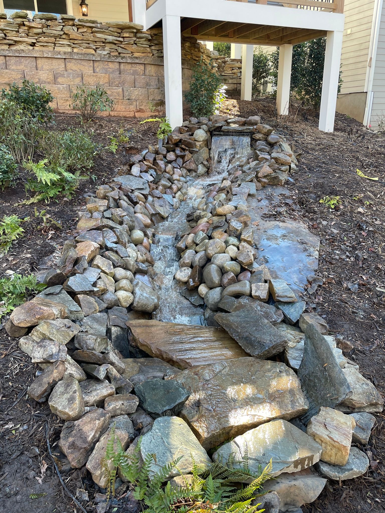 A small waterfall is surrounded by rocks in a garden.