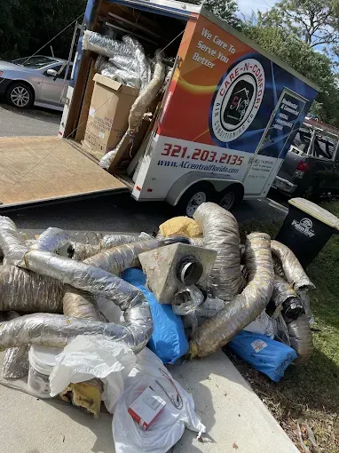 Pile of HVAC ducts and equipment spilling from a trailer, likely for installation.