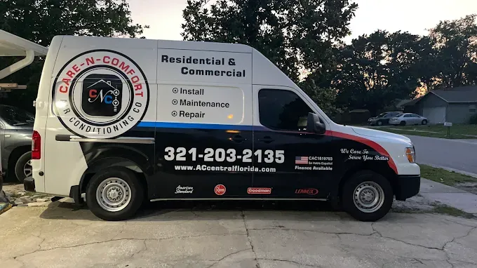 White HVAC service van with logo and contact info parked in front of a house.