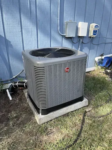 Gray Rheem air conditioning unit outside blue building.