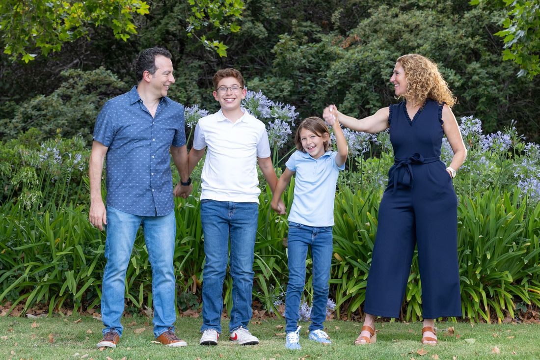 Top realtor Racquel Wilder Realty and her family smiling in a lush garden.