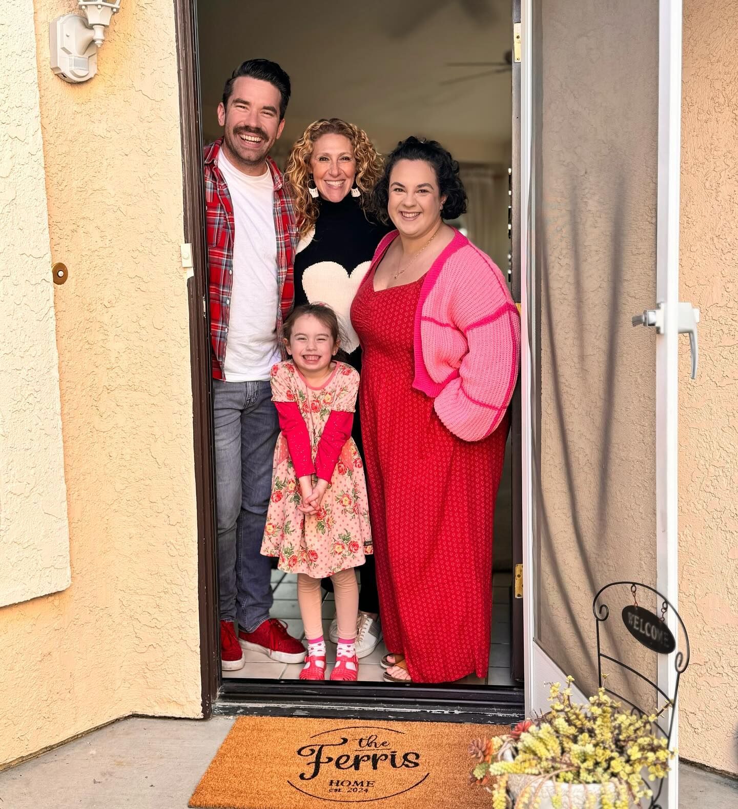 Racquel Wilder Realty clients standing in their doorway with a custom welcome mat at their new home.