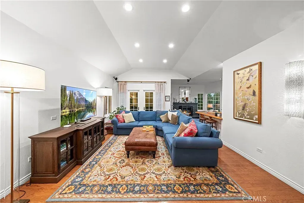 Spacious living room with blue sectional sofa, area rug, wooden floor, and a TV | Homes for Sale in Santa Clarita, CA