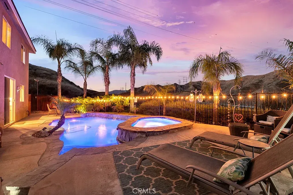 A luxury home backyard with a glowing pool at dusk.
