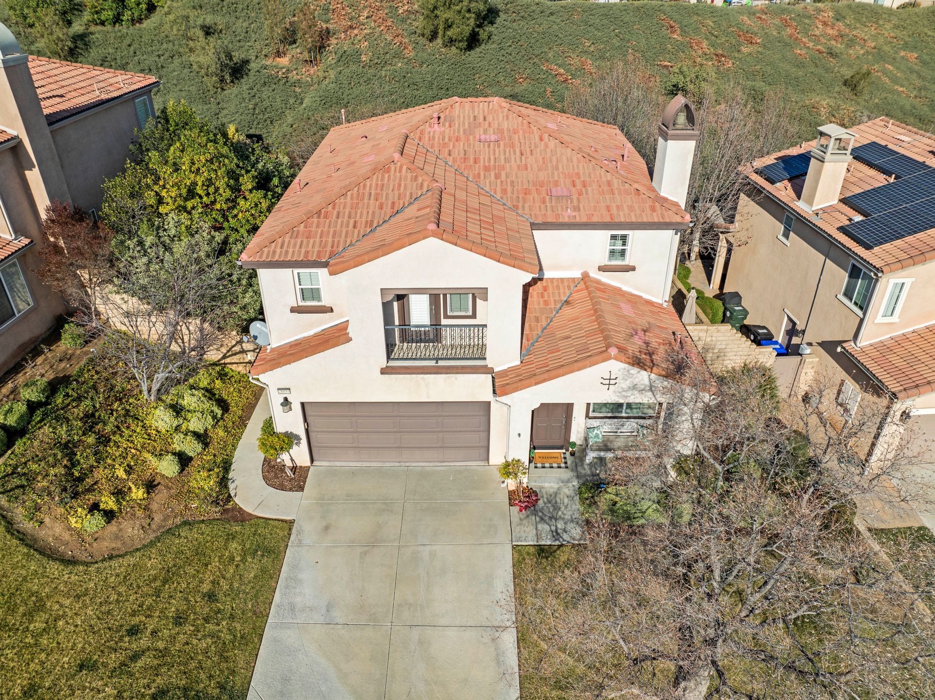 Two-story beige house with red tile roof, two-car garage, and concrete driveway | Homes for sale in Santa Clarita, CA