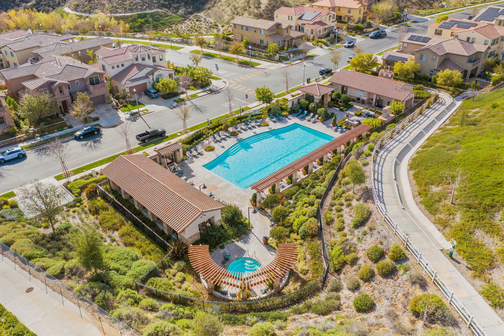 High-angle drone shot of a neighborhood recreation center, parking lot, and large blue pool.
