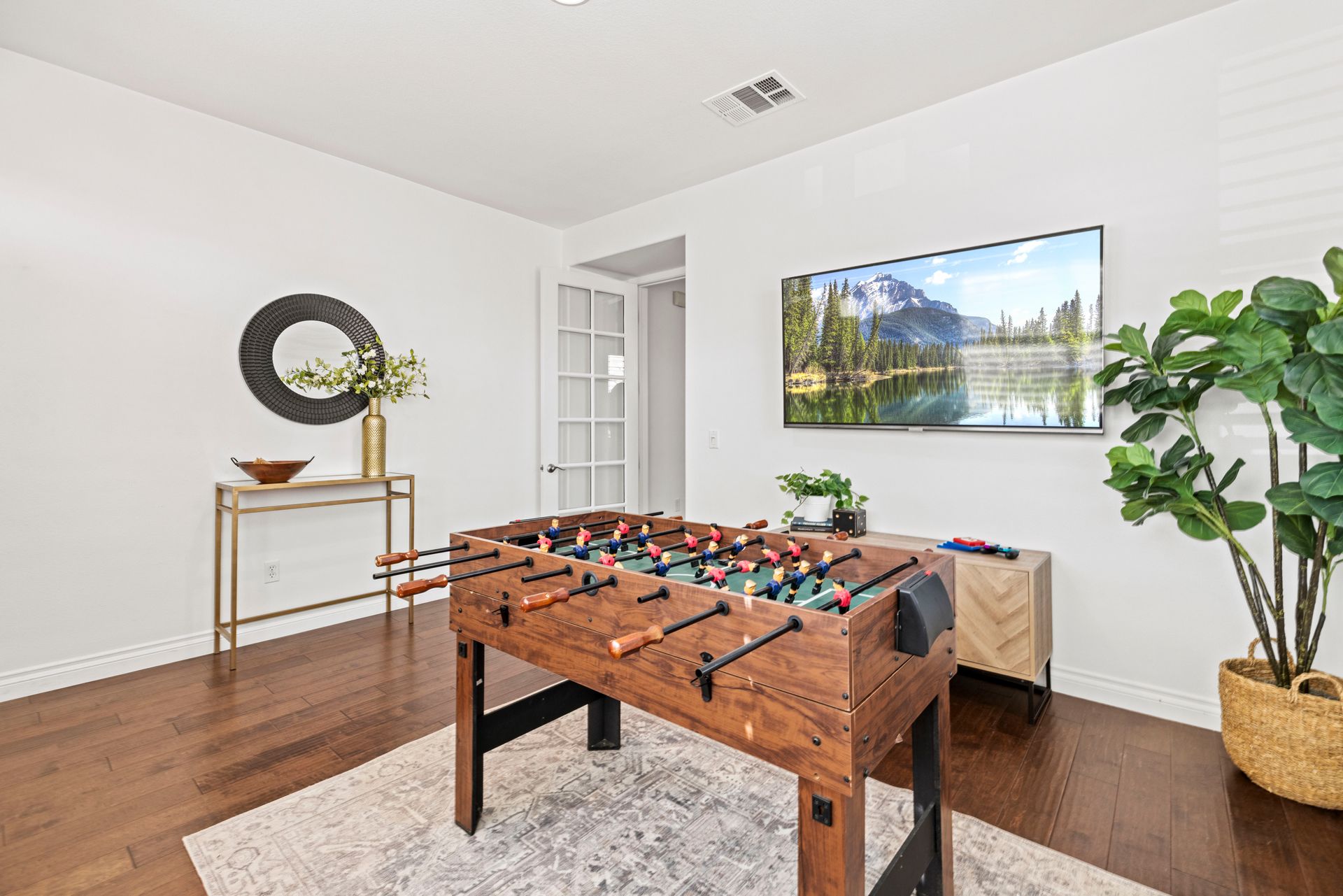 Game room with a foosball table, flat-screen television, wall decor, and indoor plants.