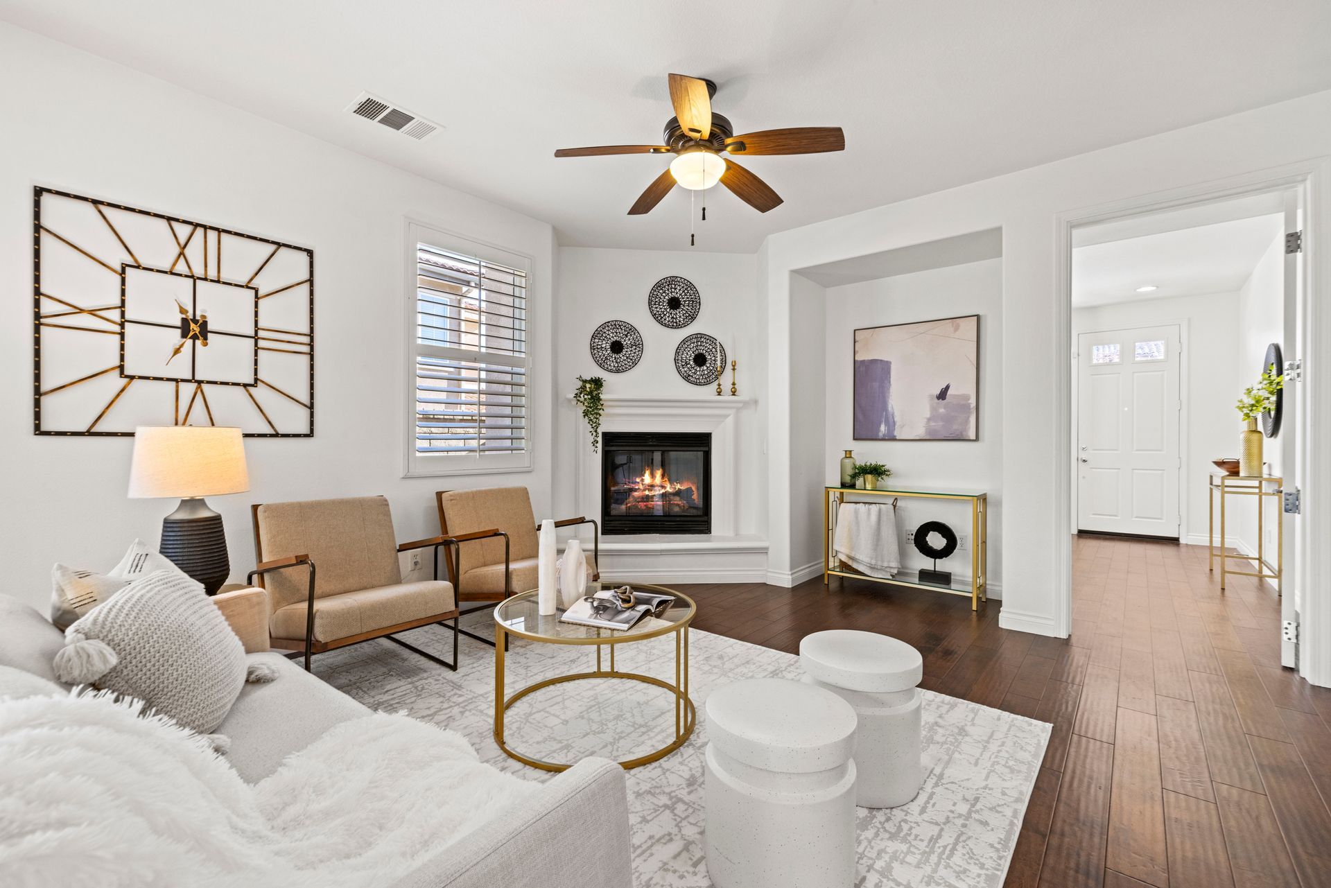 Wide-angle shot of a home living room with a fireplace, open doorways, and modern geometric wall decor.