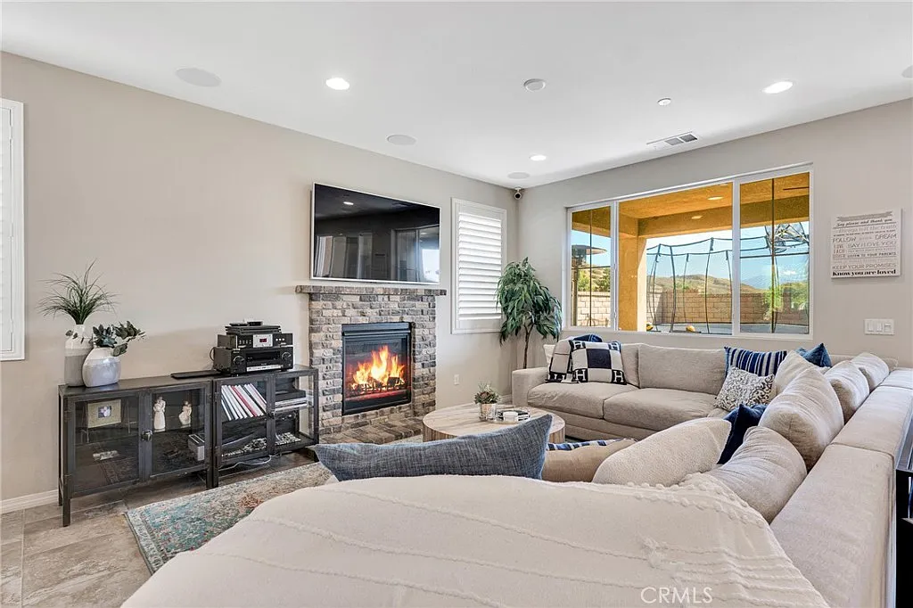 Living room with fireplace, TV, and large sectional sofa near a window | First Time Homebuyers in Santa Clarita, CA