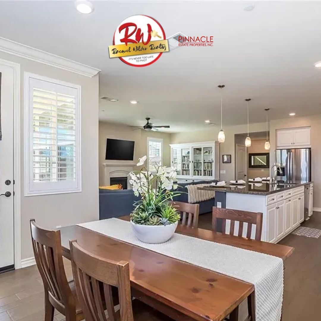 Open-concept home featuring a wooden dining table with a white runner and centerpiece, adjacent to a kitchen and living space