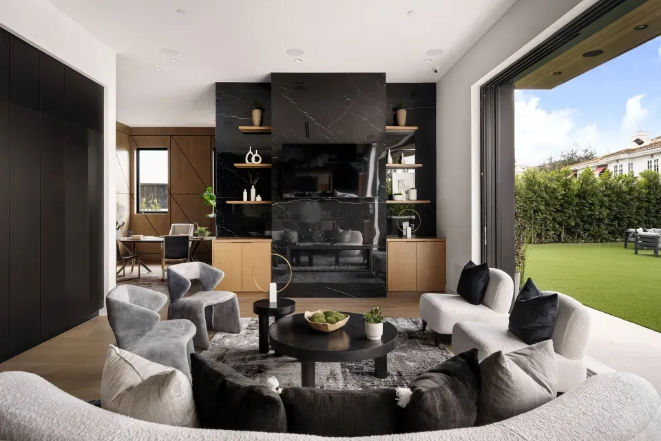 A luxury real estate living room featuring a black marble fireplace and large glass doors to the backyard.