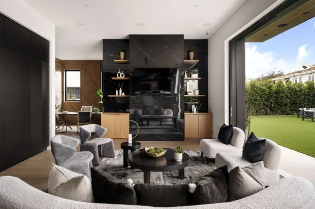 A luxury real estate living room featuring a black marble fireplace and large glass doors to the backyard.