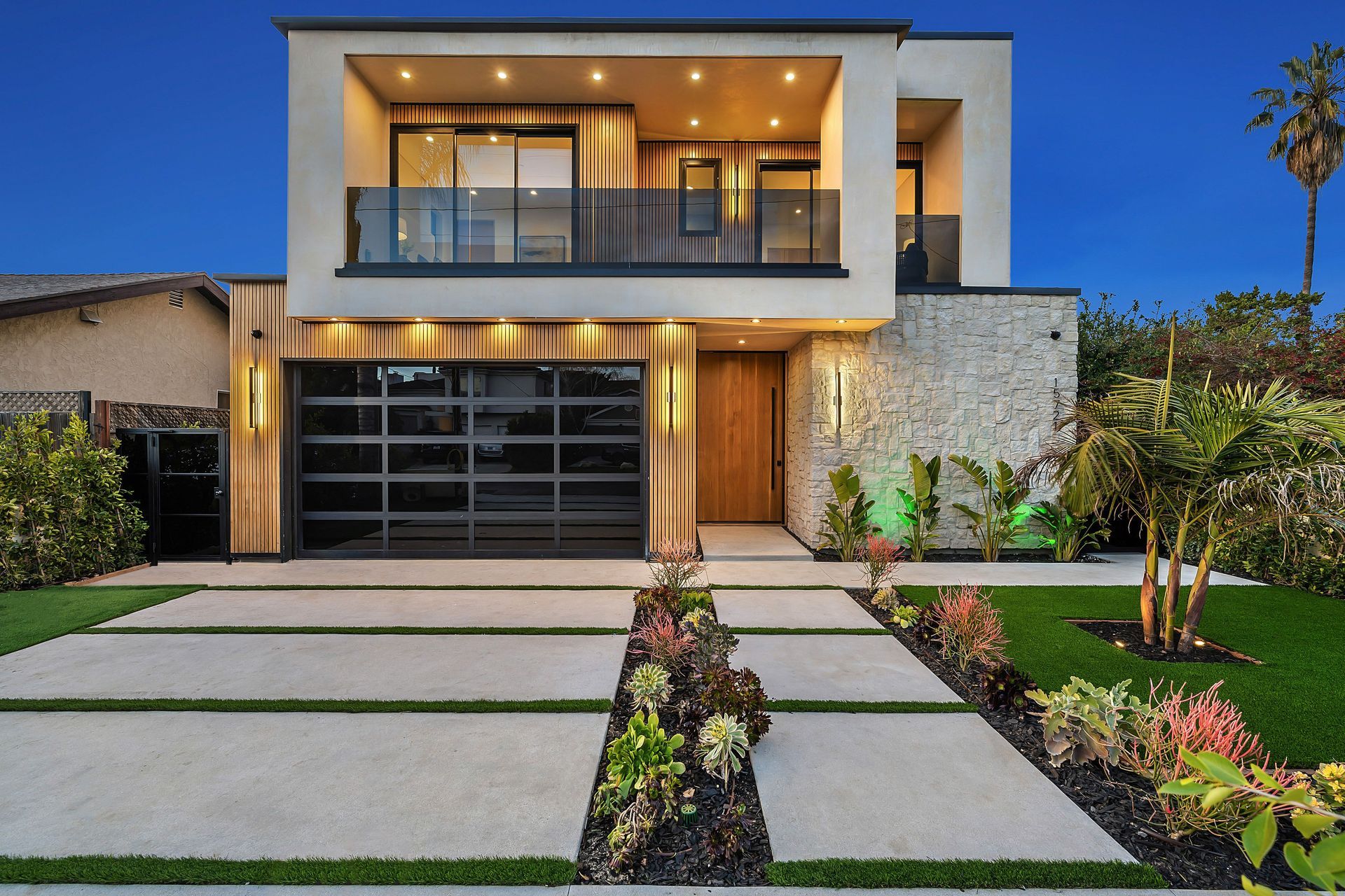 Modern two-story luxury home with a black garage door, featuring a landscaped front yard.