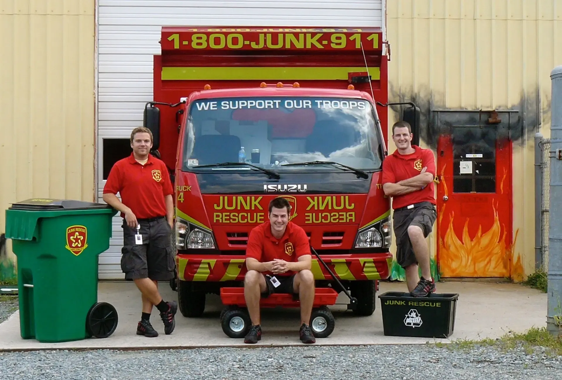 Three people in red shirts pose with a red 