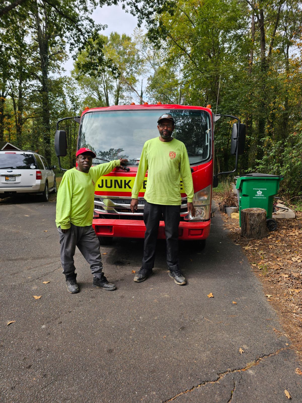 Two people in green shirts stand next to a red truck.