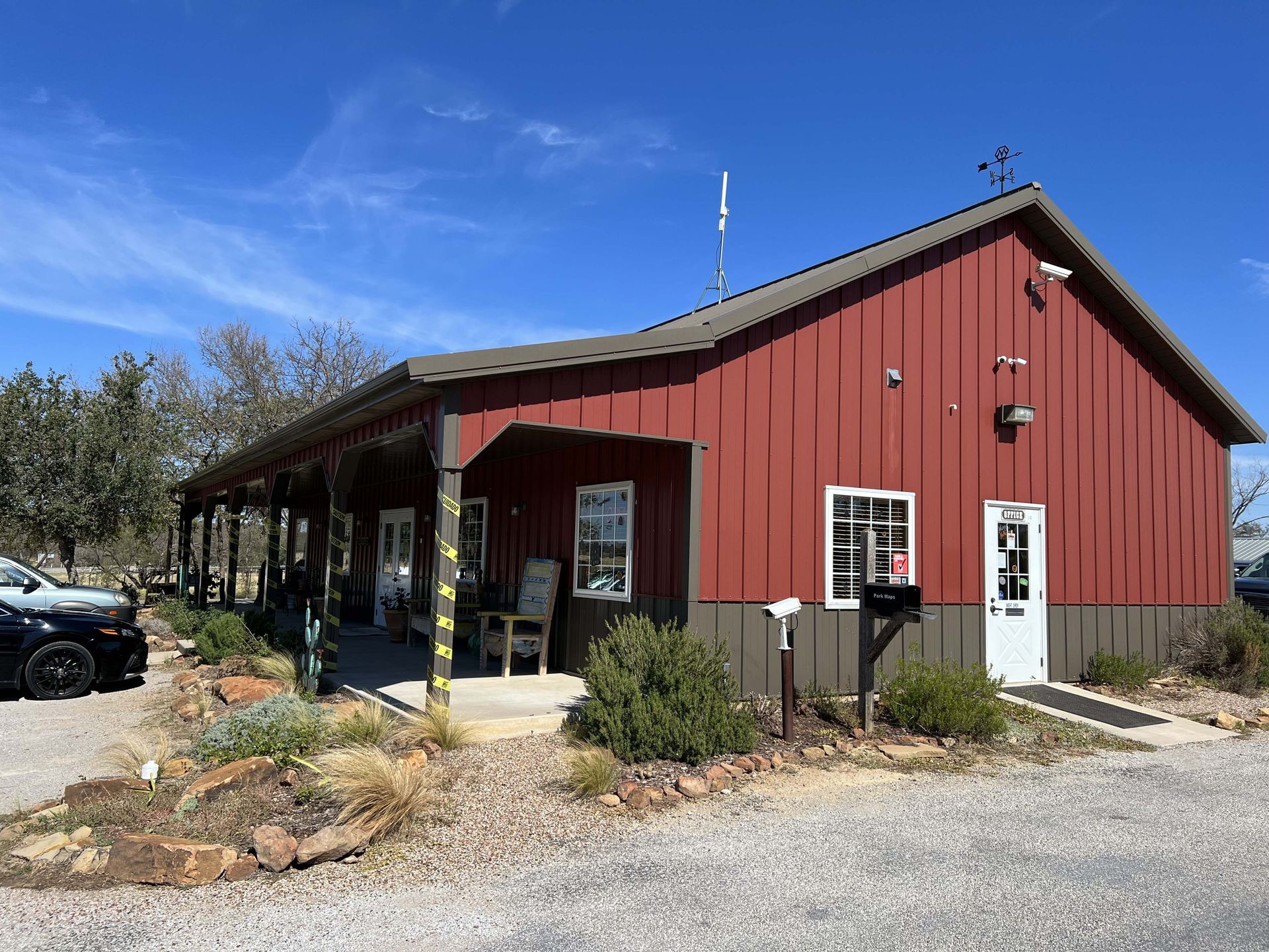 A large red barn with a porch and a car parked in front of it.