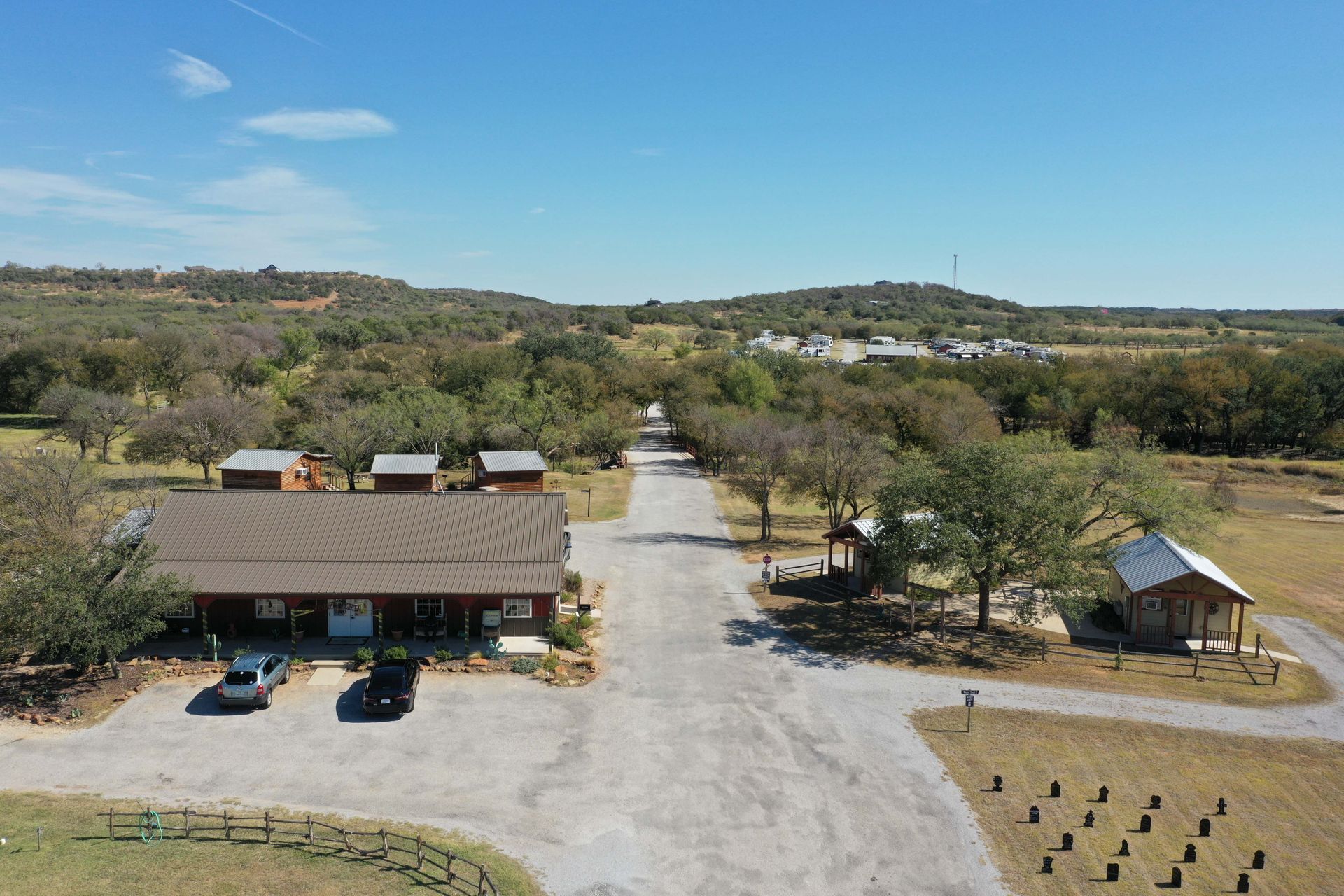 An aerial view of a house surrounded by trees and a dirt road.