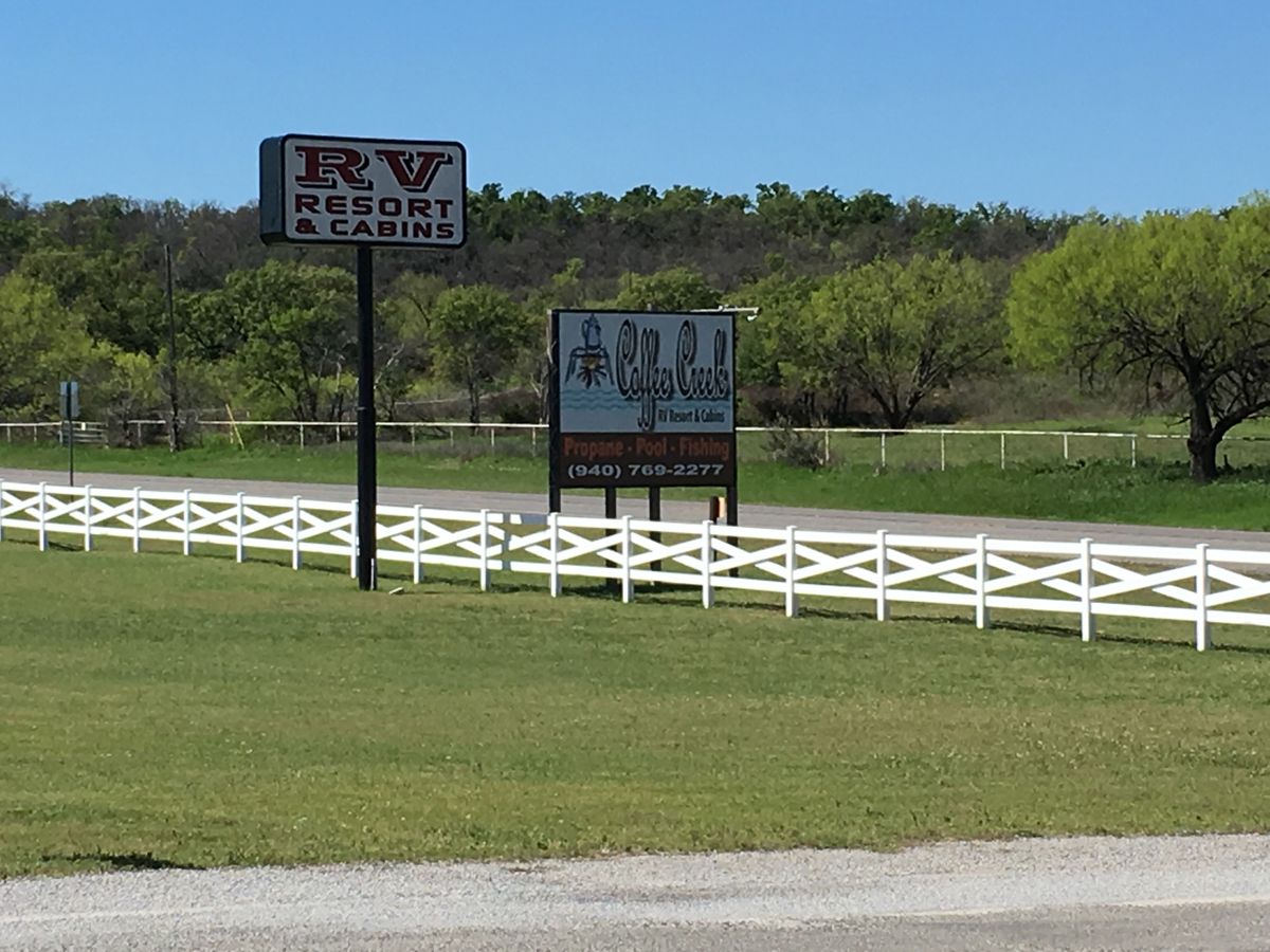 A rv resort and cabins sign is in the middle of a grassy field