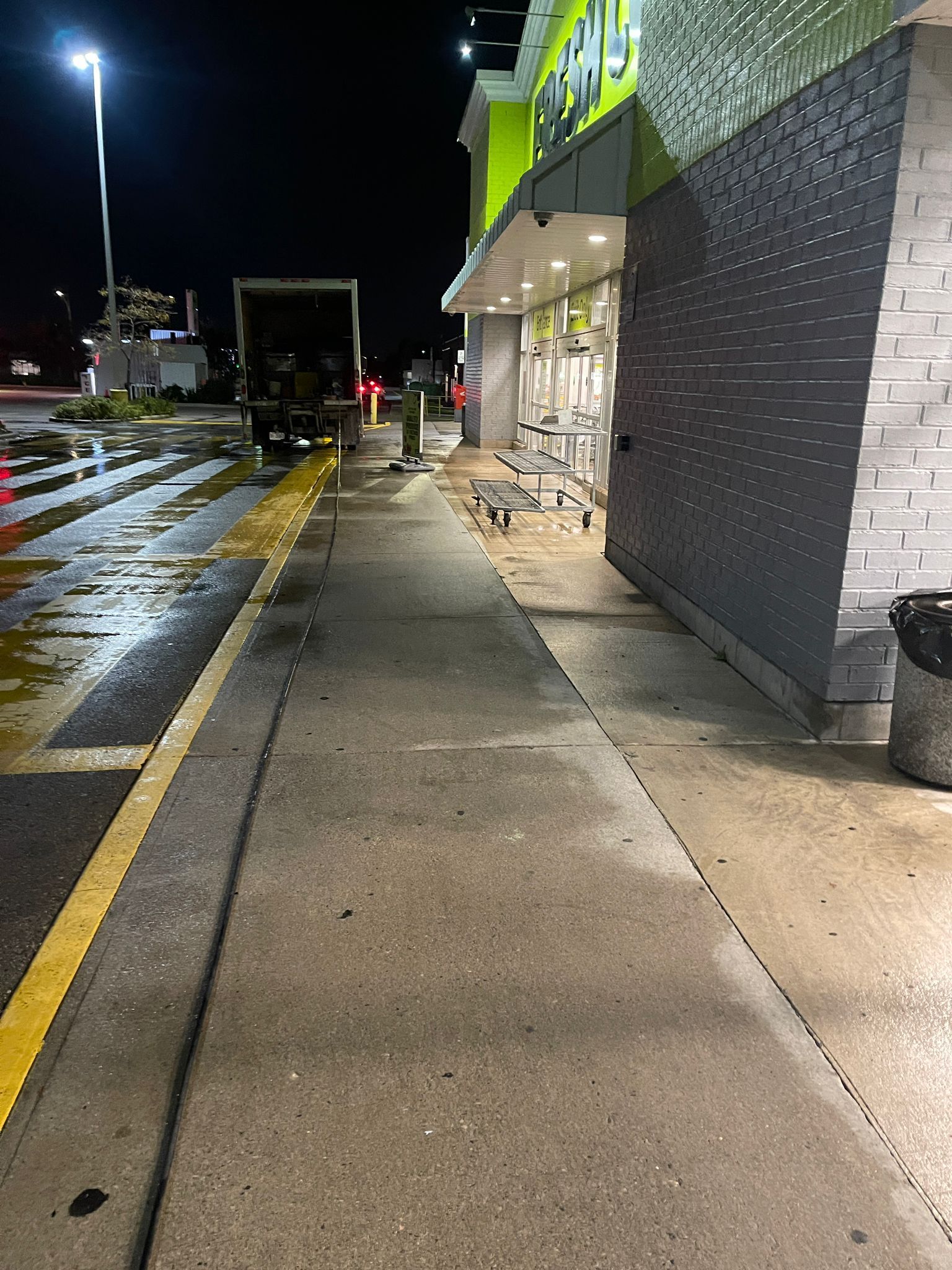 Sidewalk in front of a green and black building with debris scattered on the ground at night.