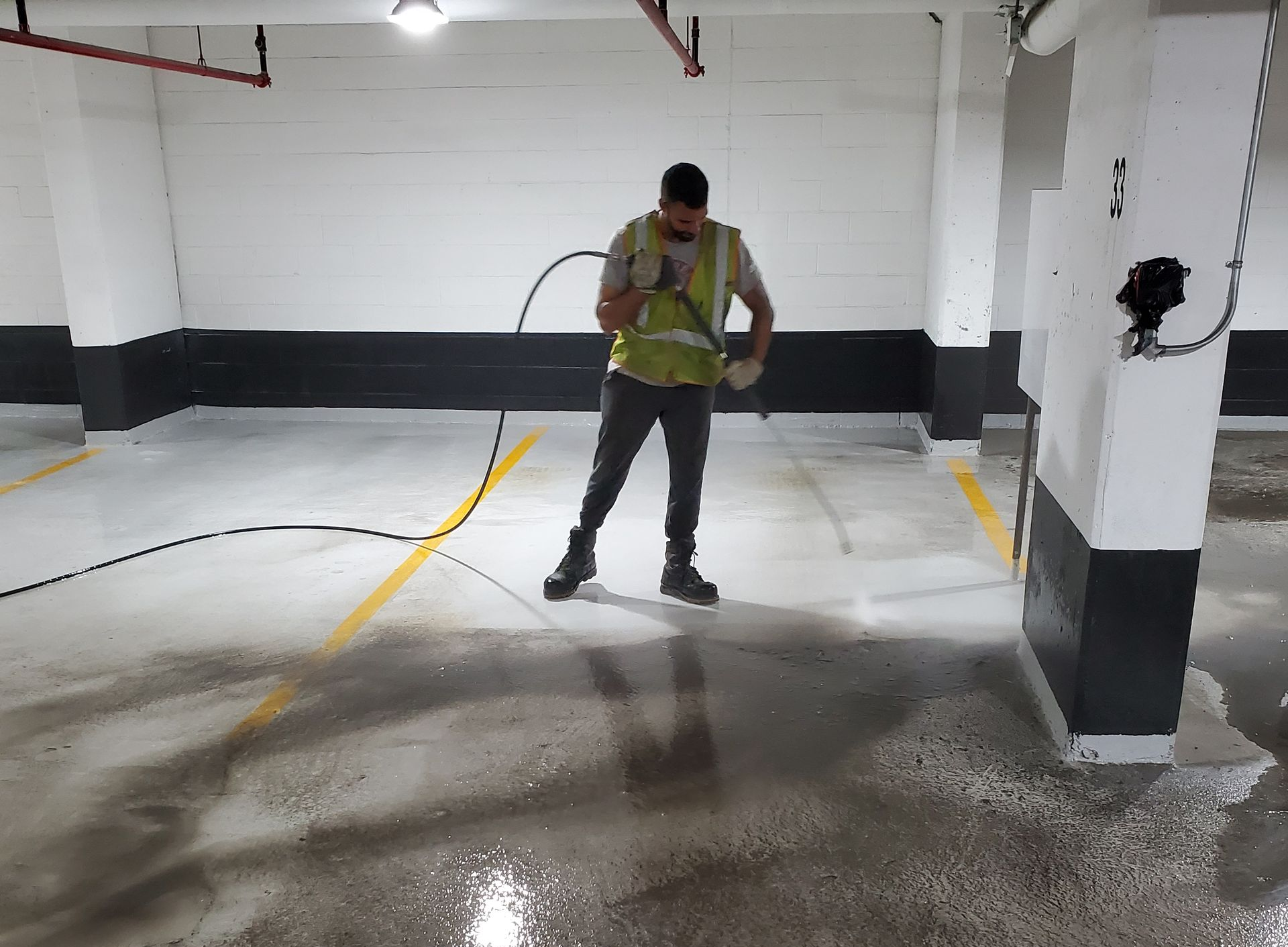 Person spraying liquid on a freshly painted parking garage floor.