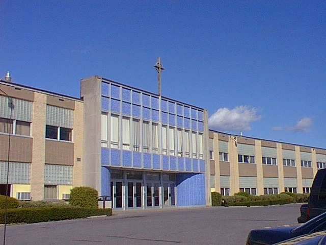 Wide view of a beige building with blue glass entrance under a clear sky