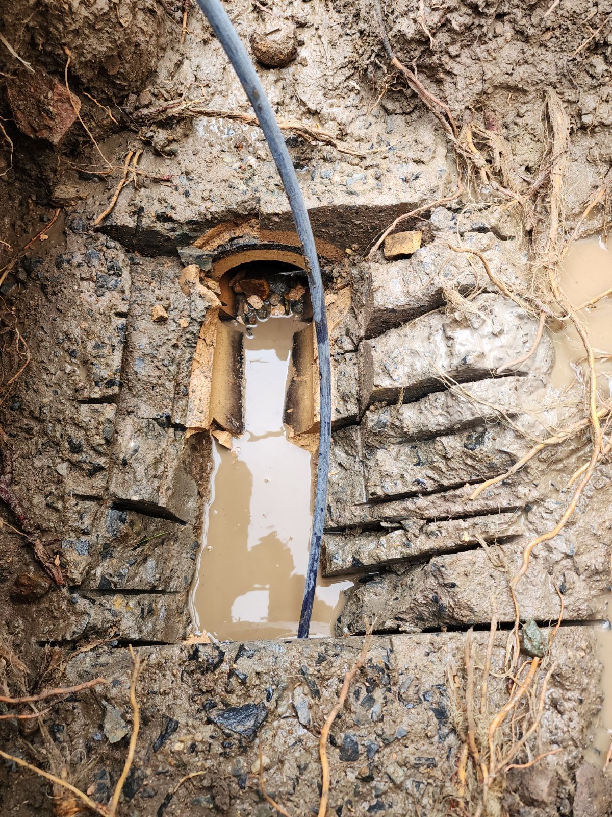 An Excavated, Concrete-lined Drainage Pipe or Channel Partially Filled With Muddy Water — PlumbPlus in Kawana, QLD