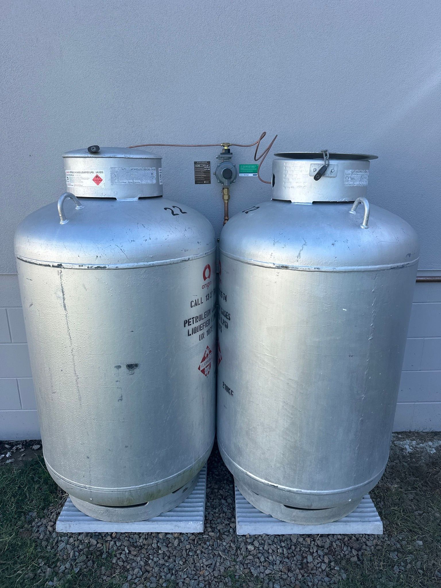 Two Large Silver Propane Tanks Stand Side-by-side on White Pads— PlumbPlus in Kawana, QLD
