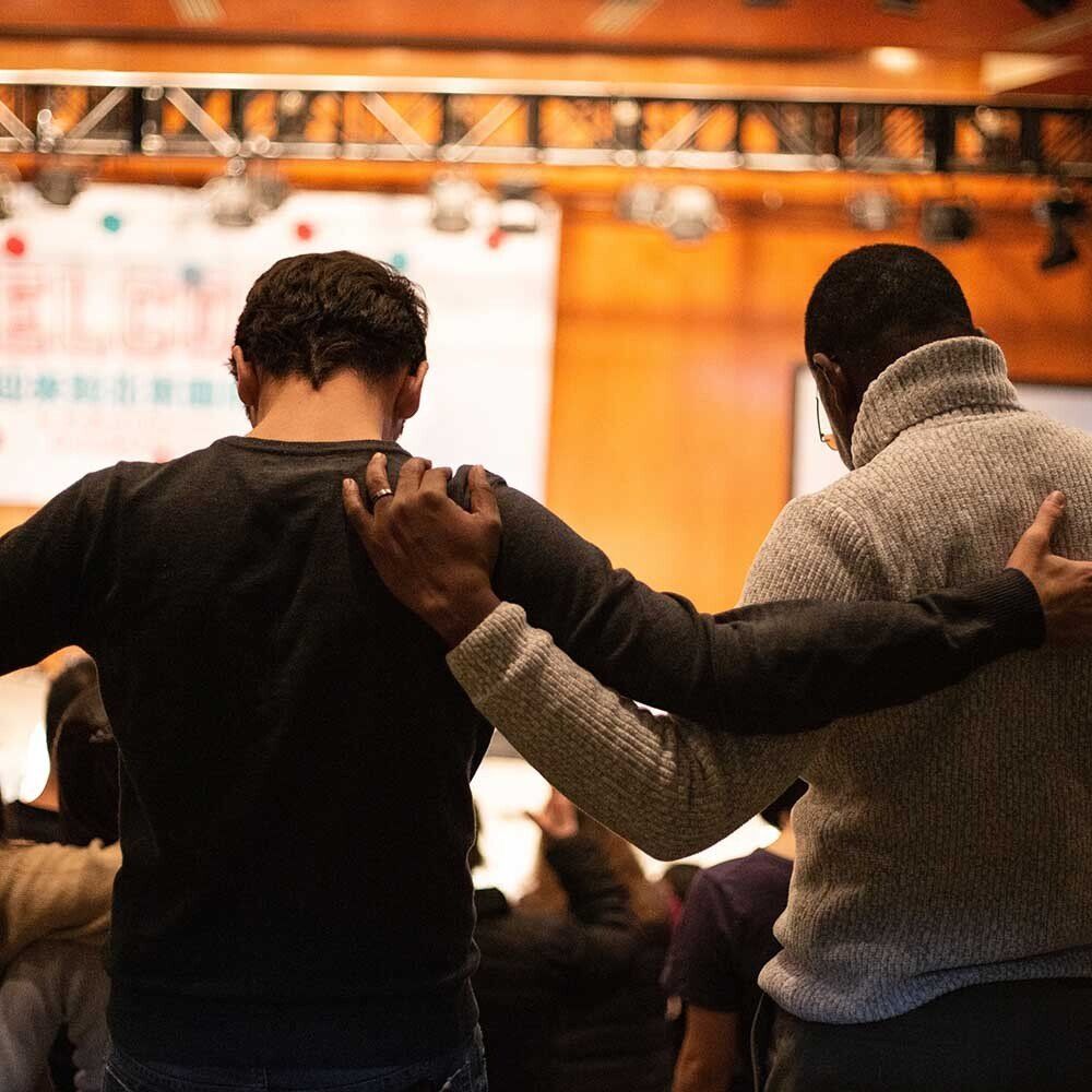 Two men standing next to each other with their arms around each other 's shoulders