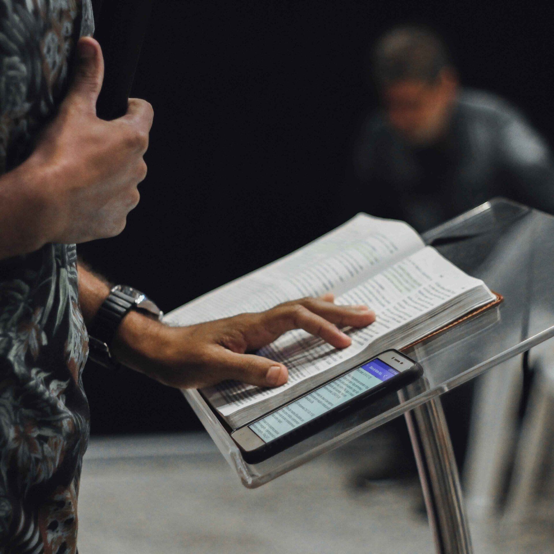 A man is holding a bible and a cell phone