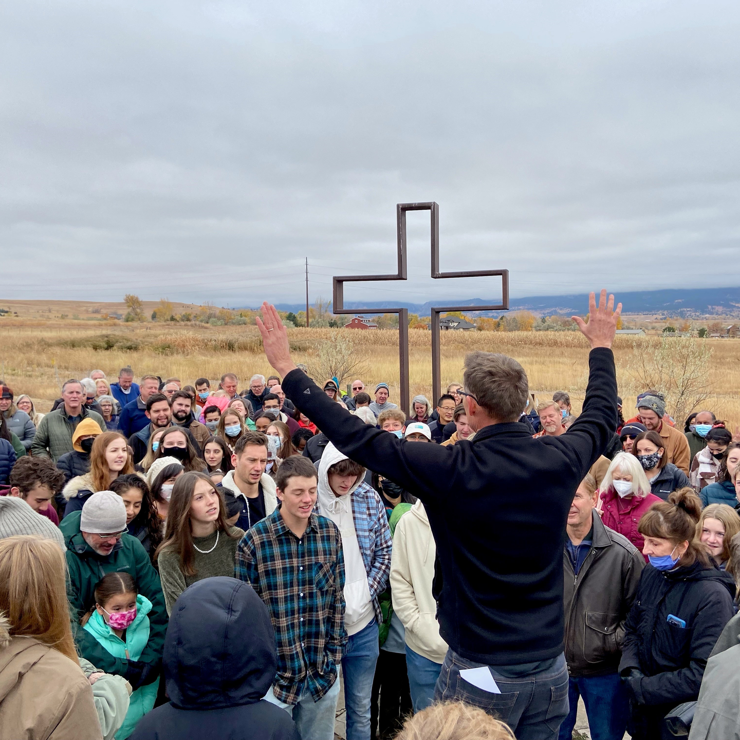 A man is holding a cross in front of a crowd of people.
