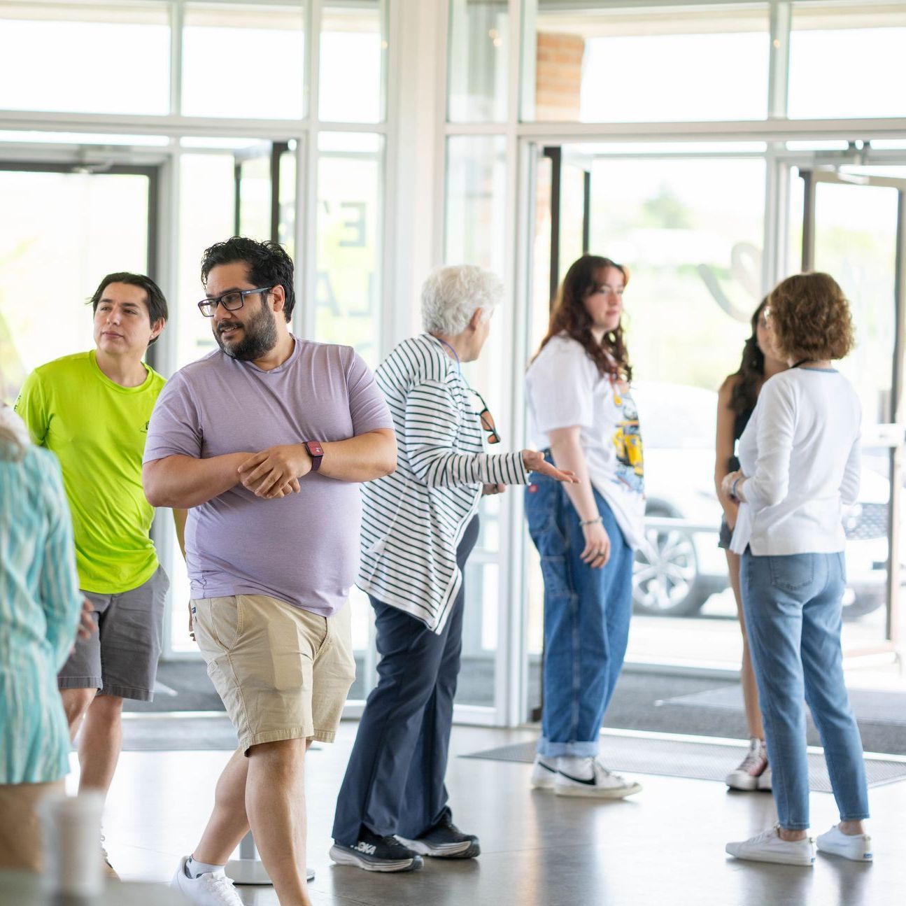 A group of people are standing in a room talking to each other.